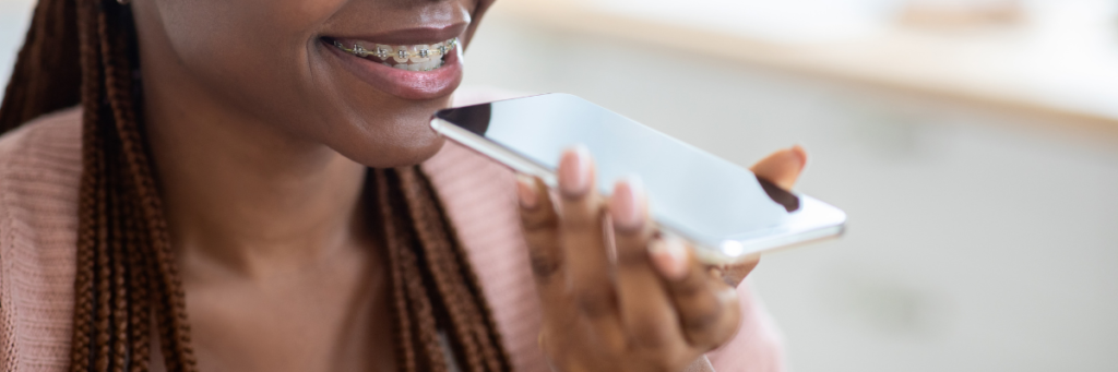 A woman with braces uses her phone to conduct a voice search