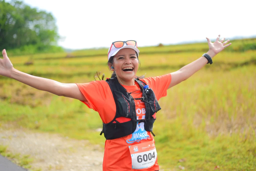 A woman wearing an orange Global 6k shirt celebrates taking part in the event.